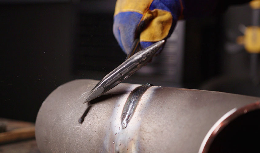 Slag being chipped off a stick weld done on a pipe