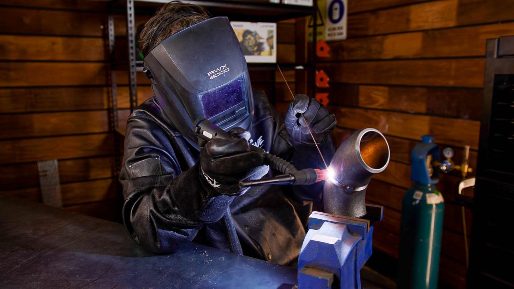 Sitting down, TIG welding a pipe 